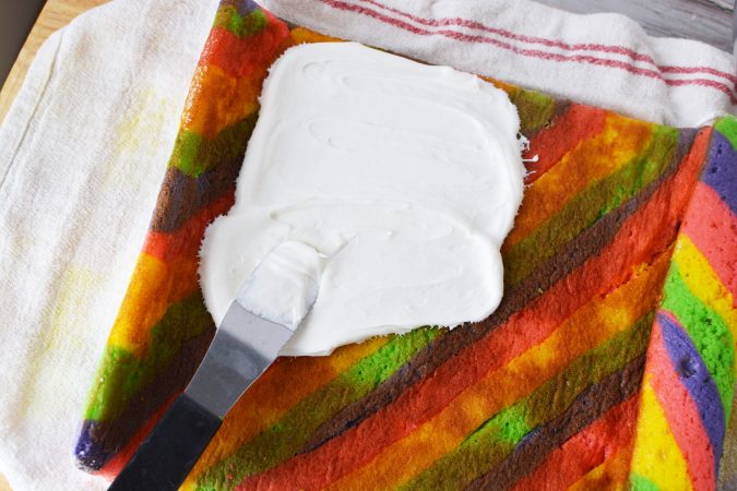 colorful cake being iced with white frosting