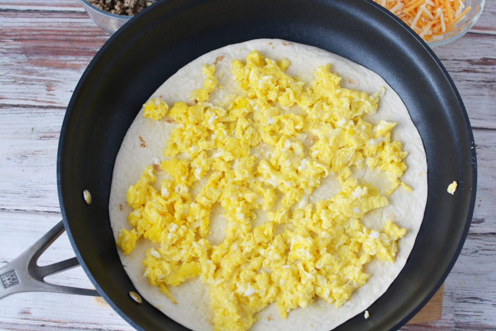 Adding scrambled eggs to a large tortilla