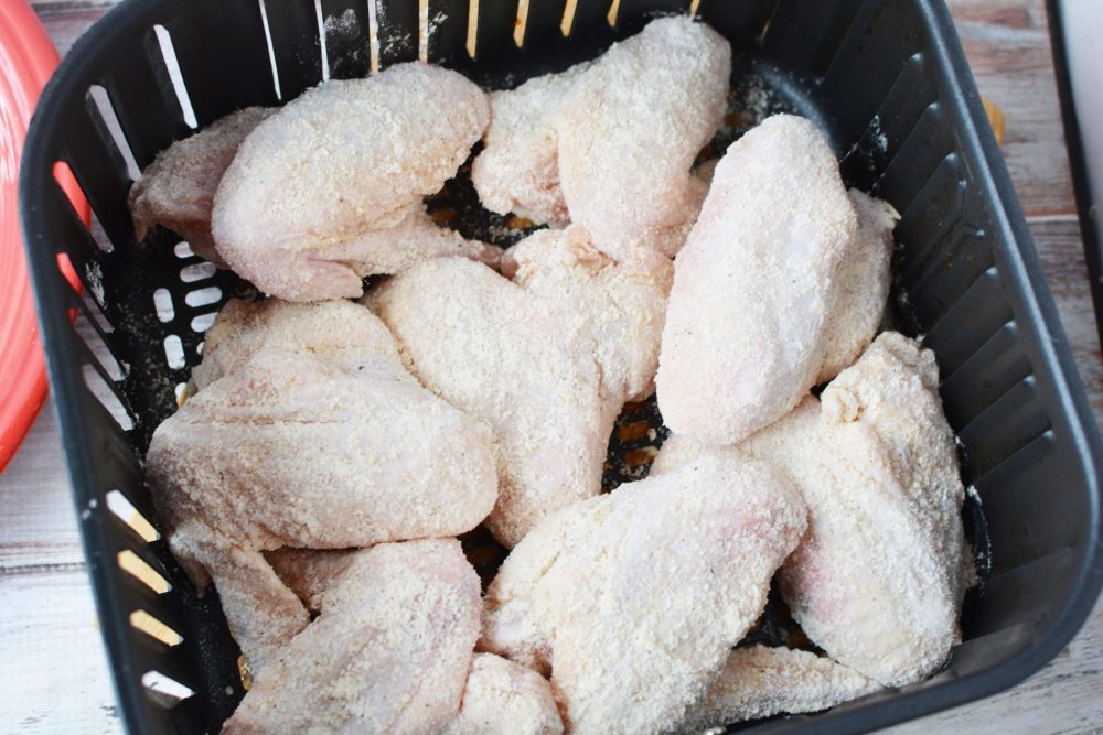 wings in an air fryer basket with coating 