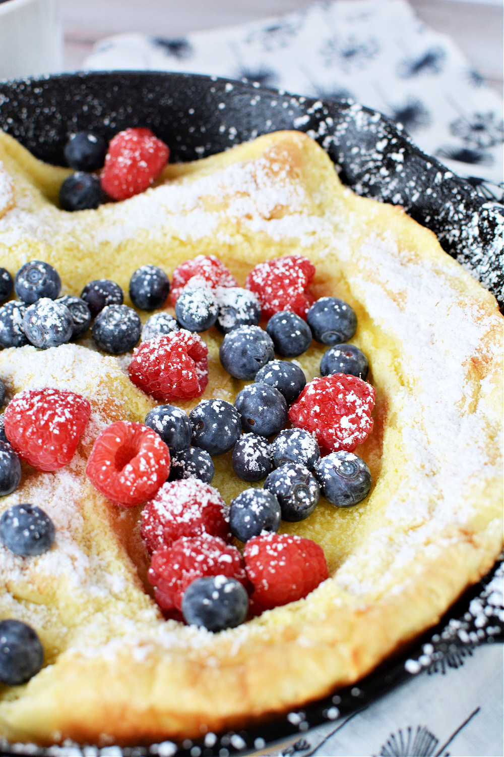 Puffed Pancake sprinkled with powdered sugar and covered with fresh berries