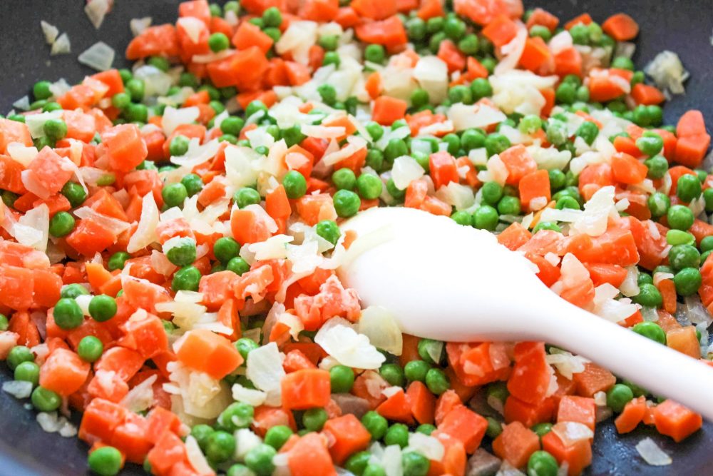 Cooking peas, carrots, and onions in a skillet 