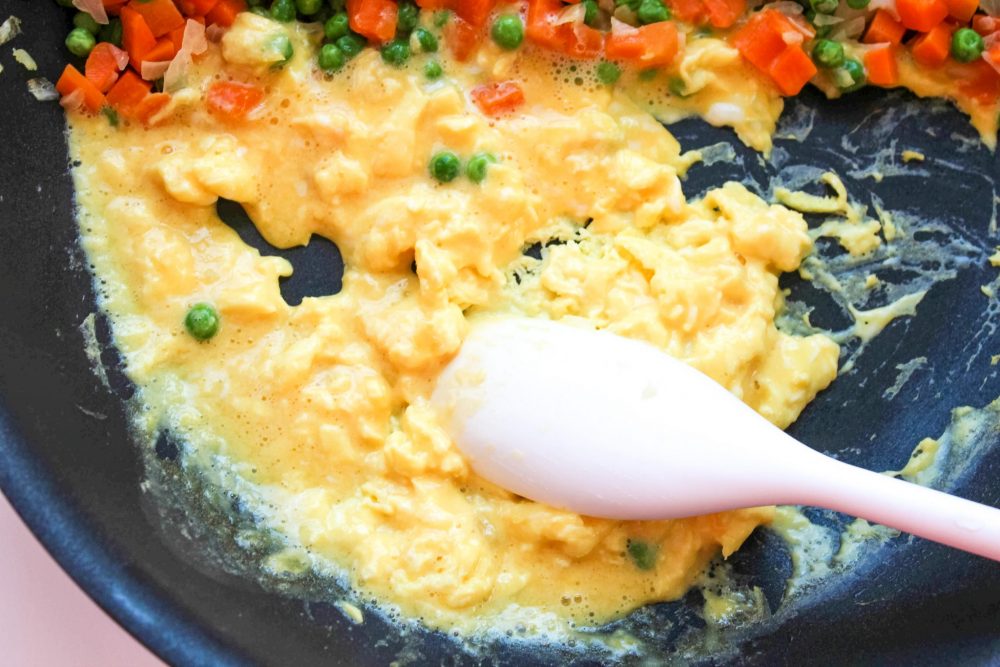 Adding eggs to the skillet with the vegetables 