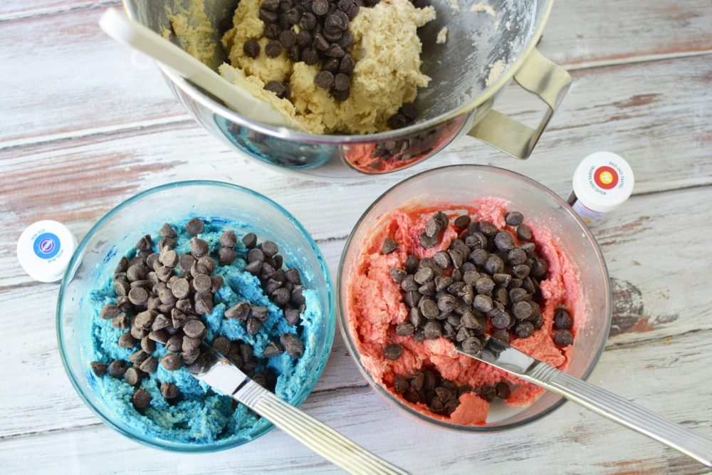 three bowls of cookie dough - one that is blue, one that has red dough, and one that has uncolored dough