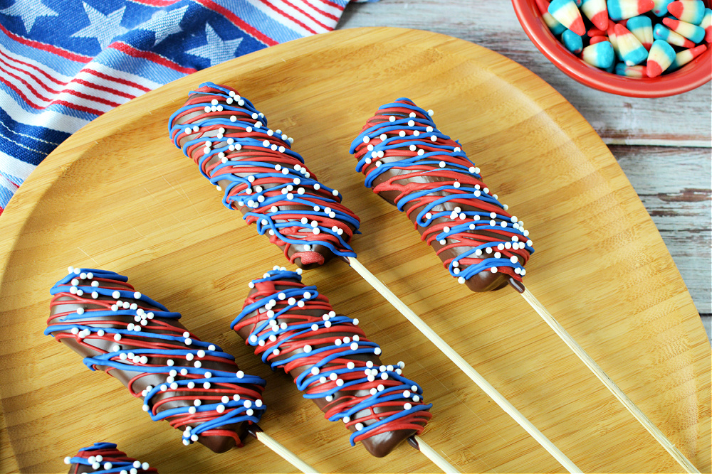Four Red, White & Blue Marshmallow Pops on a bamboo plate