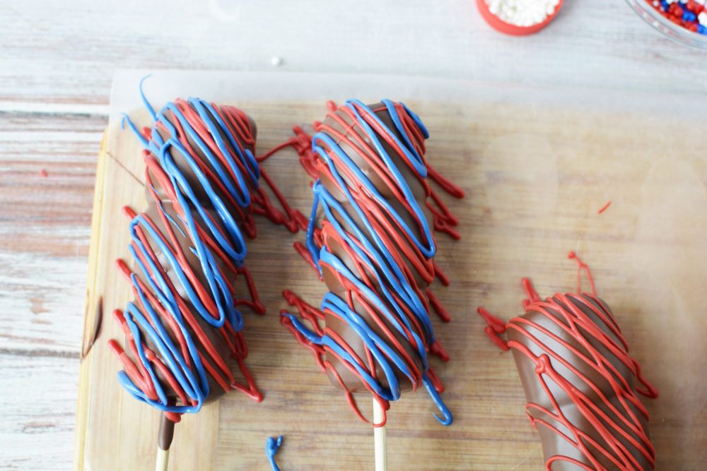 Adding melted red and blue chocolate on top of the chocolate covered marshmallows 