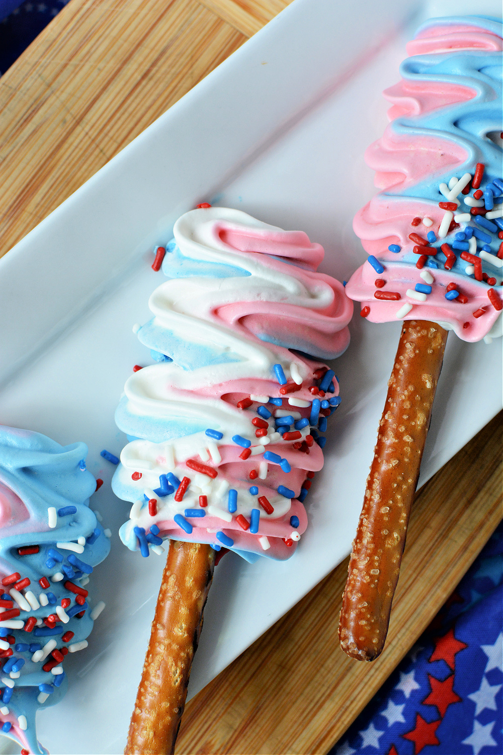 A close-up of red, white and blue meringue pops on a white plate 