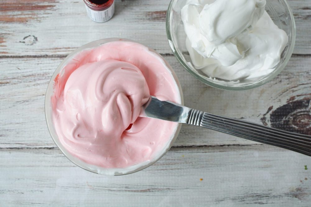 A bowl of pink meringue next to a bowl of white meringue