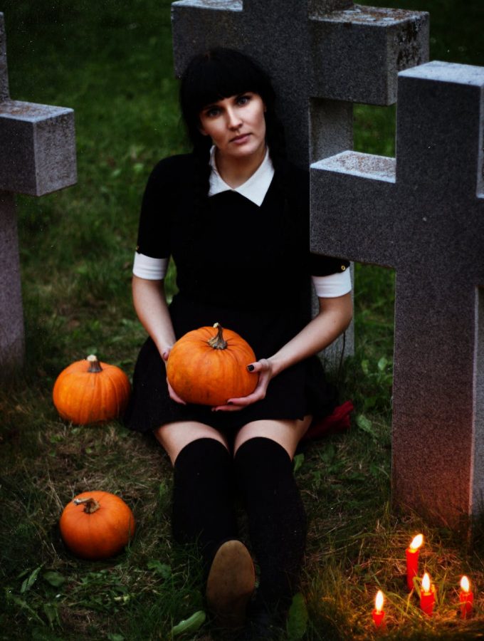 Girl in black sitting with pumpkins at a grave