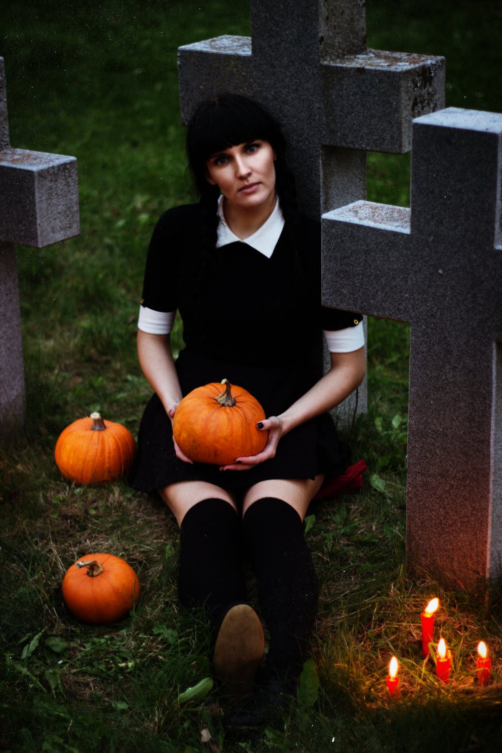 Girl in black sitting with pumpkins at a grave 