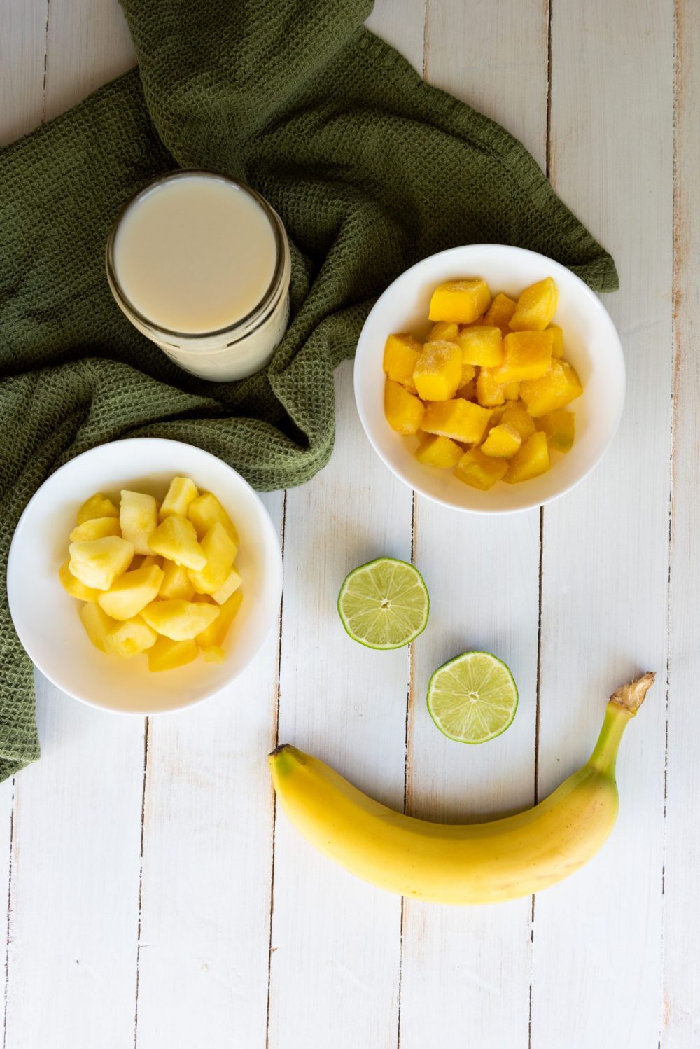 coconut milk, chunks of frozen mango and frozen pineapple and lime wedges mint leaves and banana