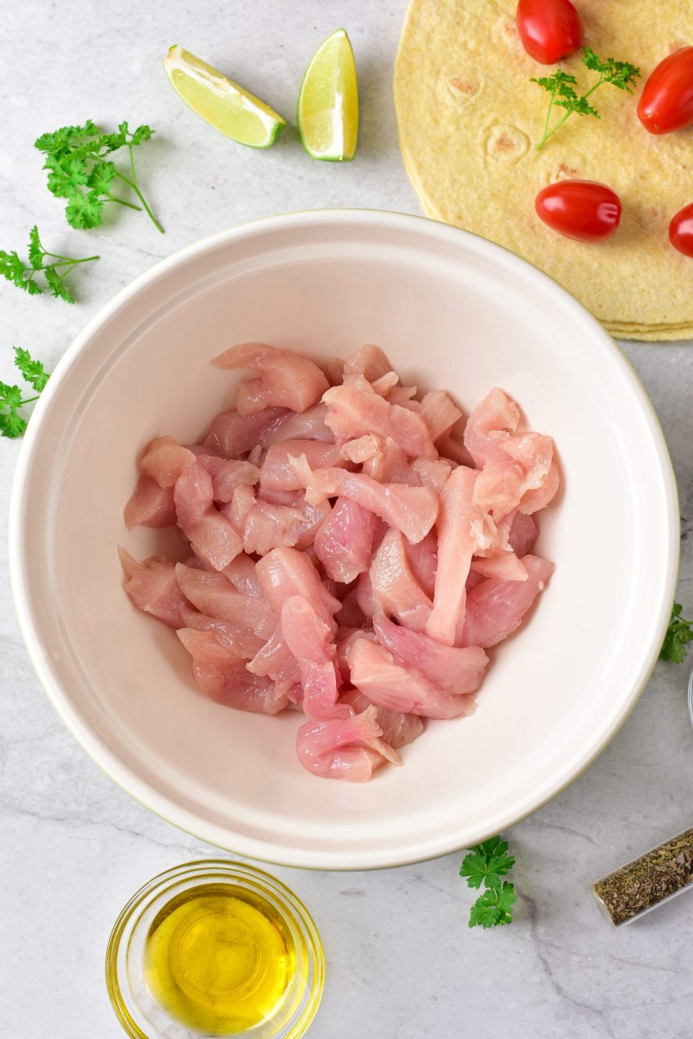 Strips of raw chicken in a mixing bowl
