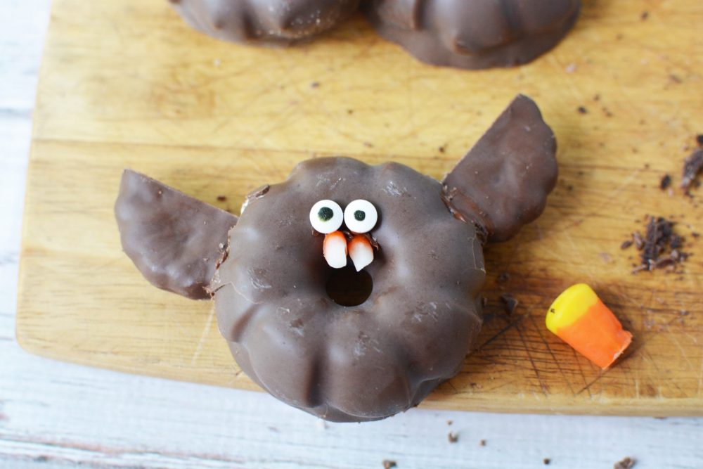 Adding googly eyes and candy corn teeth to the chocolate bat cookies 