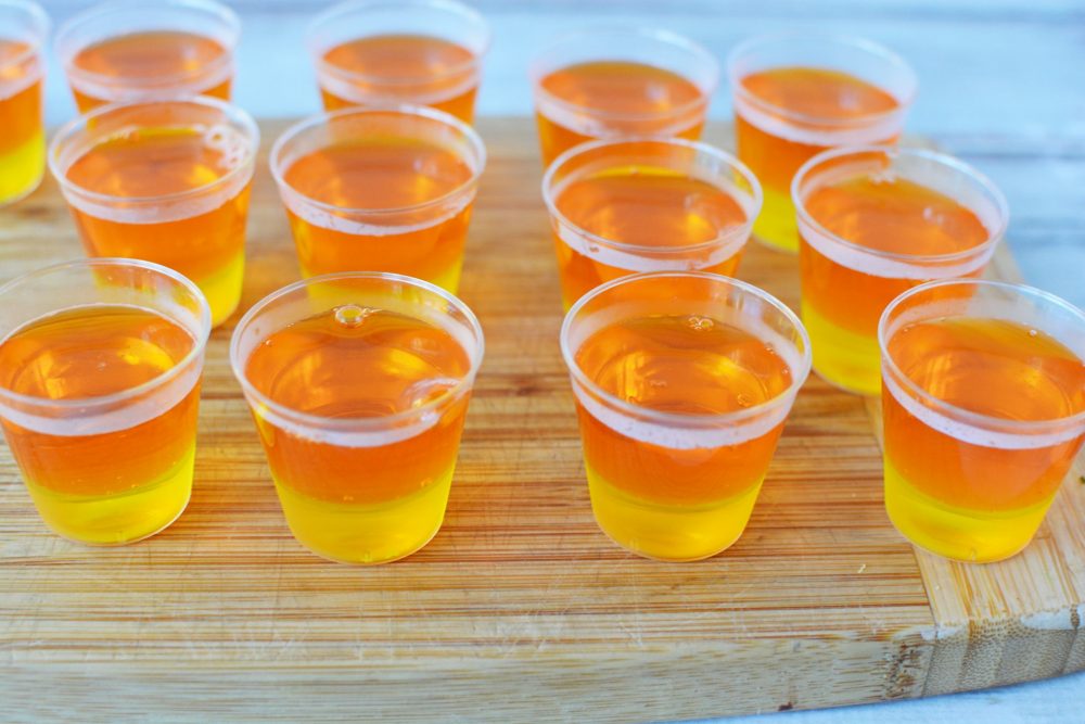 The orange and pineapple layered jello in plastic shot glasses 