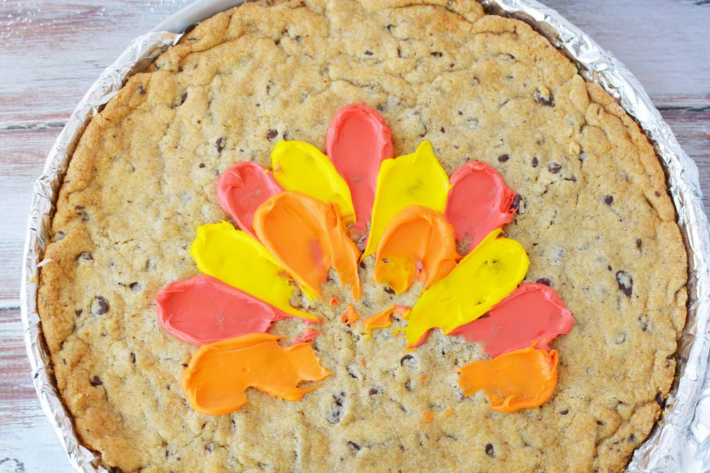 Adding red and yellow and orange frosting to the cookie to look like turkey feathers 