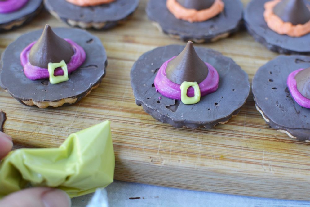 Using melted chocolate to decorate the Halloween cookies so they look like a Witch's Hat 