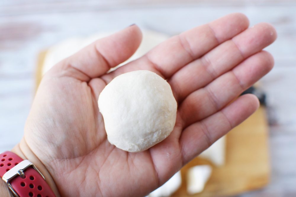 Brie-filled biscuit dough rolled into a ball and sitting in someone's hand 