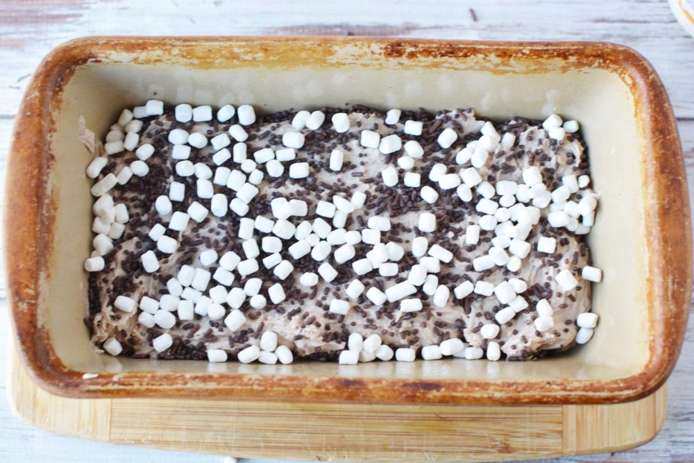 Topping the batter with marshmallows and chocolate sprinkles 