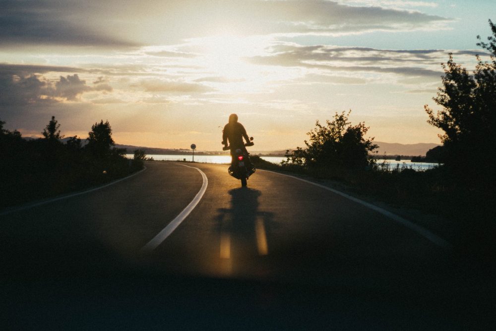 person riding a motorcycle through the sunset