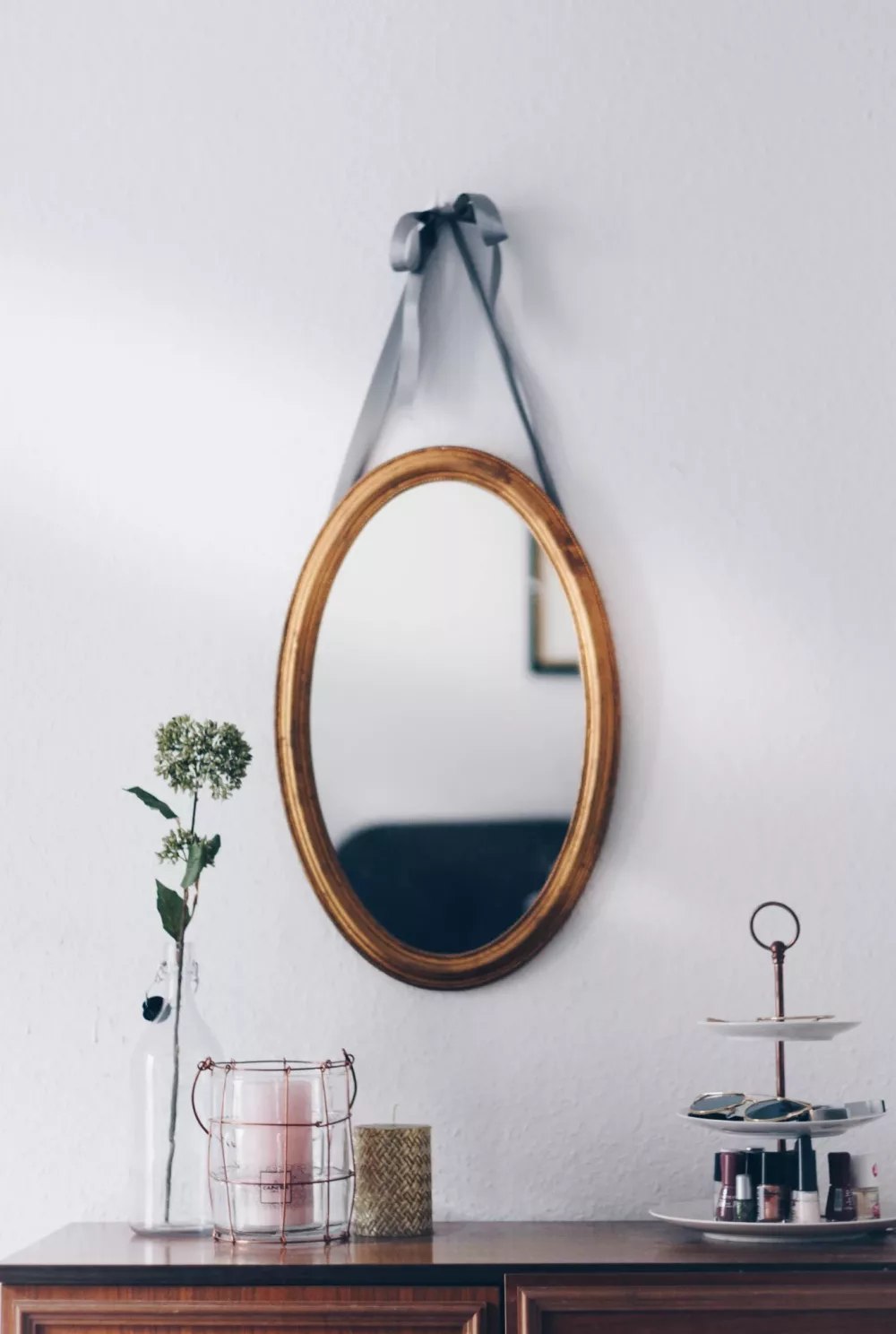 gilded oval mirror hanging on the wall
