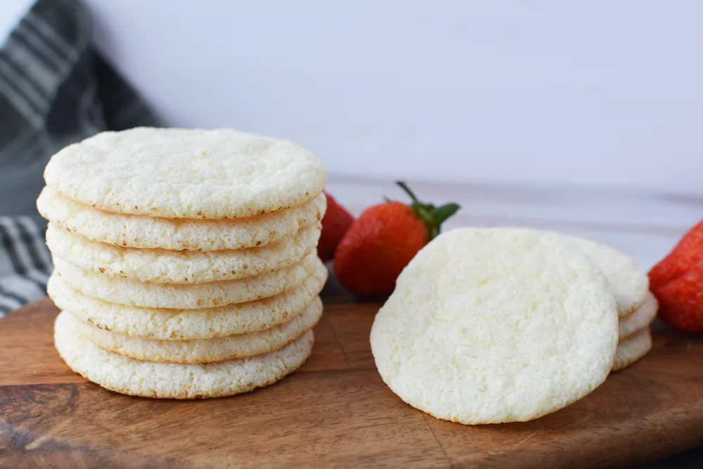 stack of Angel Food Cake Mix Cookies on a wooden cutting board with fresh strawberries in the background
