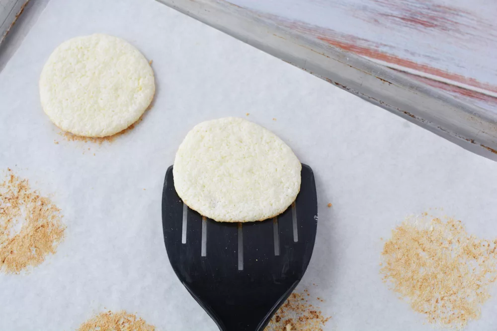 Angel Food Cake Mix Cookies on a cookie sheet lined with parchment paper and being removed with a black plastic spatula