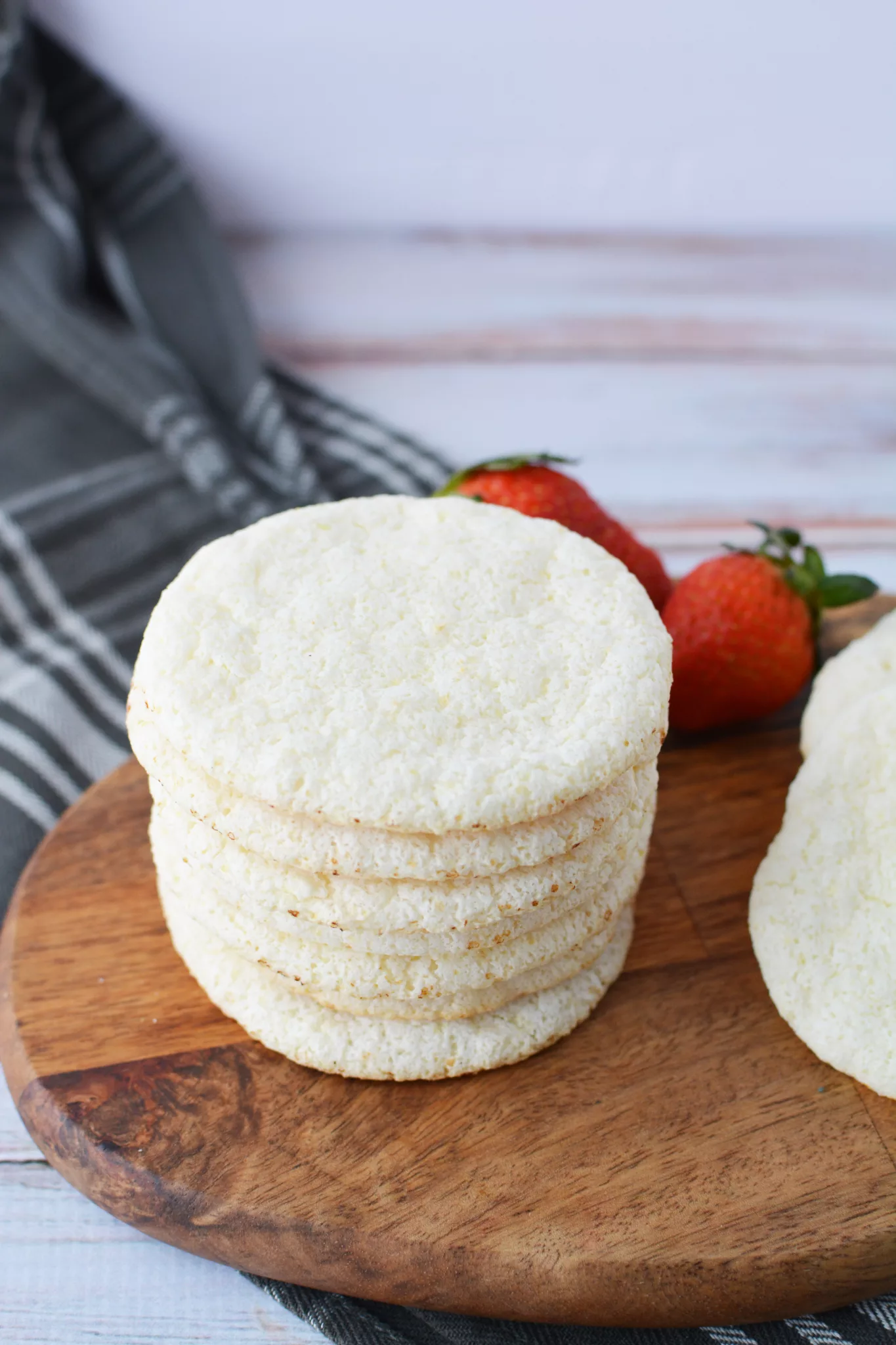 Angel Food Cake Mix Cookies on a wooden cutting board with fresh strawberries in the background