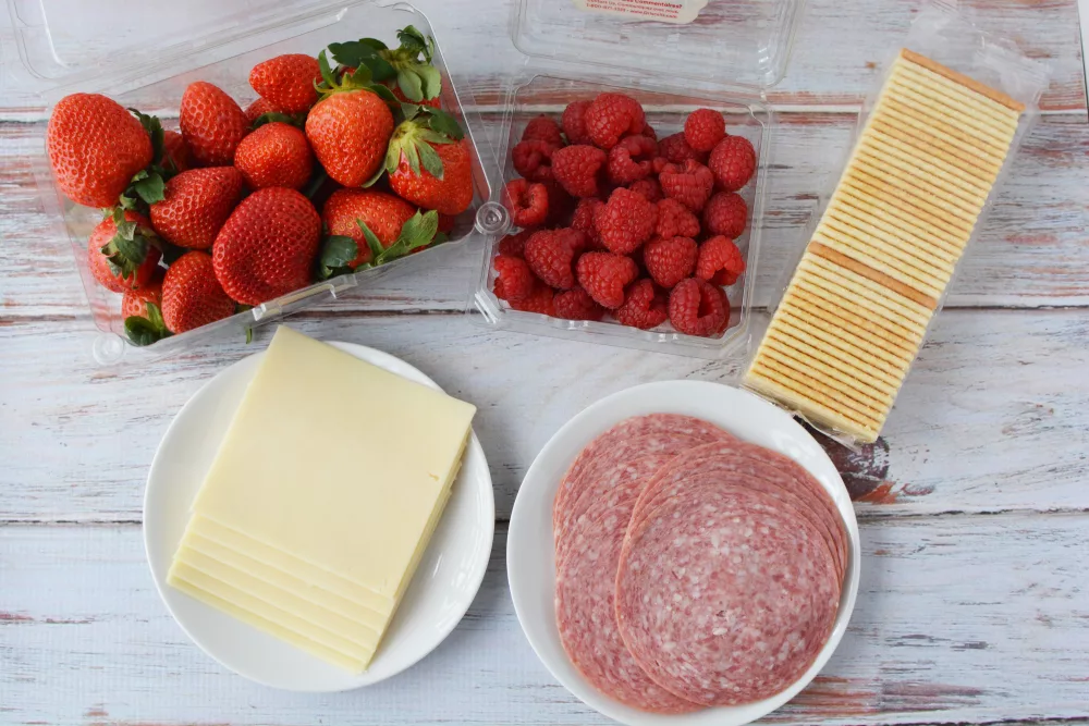 a variety of cheese slices and salami and berries