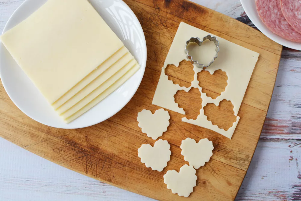 use a heart shaped cookie cutter to cut heart shapes into the slices of cheese