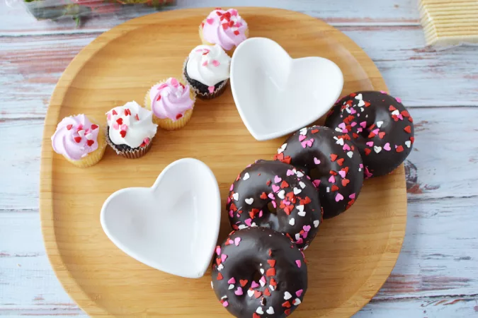 Starting with the largest items, place them on the platter: donuts and cupcakes.