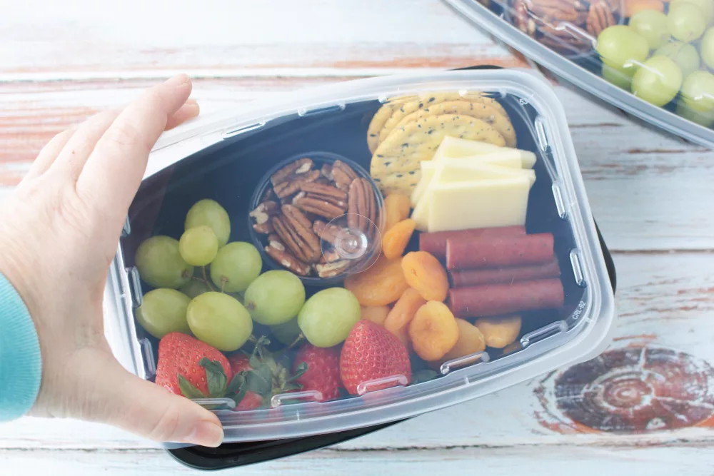 a fruit and meat and cheese filled Mini Charcuterie Box with lid