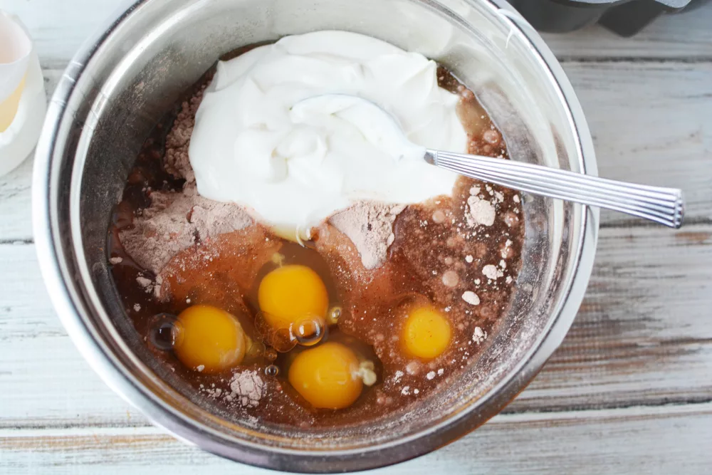 eggs, sour cream and red velvet mix in a bowl