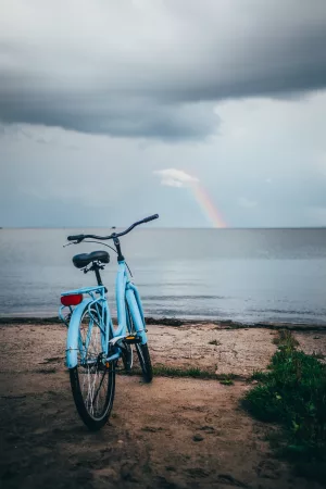 blue beach cruiser bike on the beach in front of a rainbow