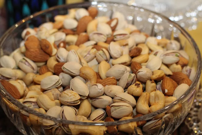 A crystal bowl full of pistachios, cashews and almonds