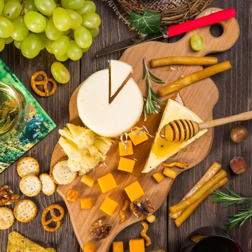 Snack board of cheese, crackers, honey, fresh fruit and pretzels