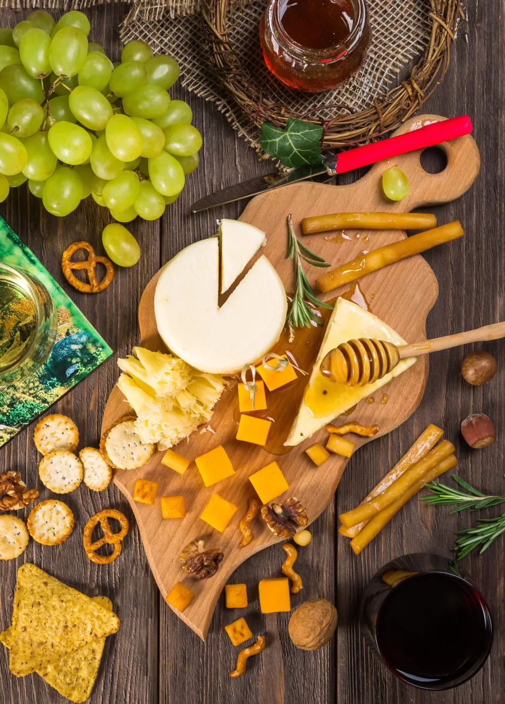 Snack board of cheese, crackers, honey, fresh fruit and pretzels
