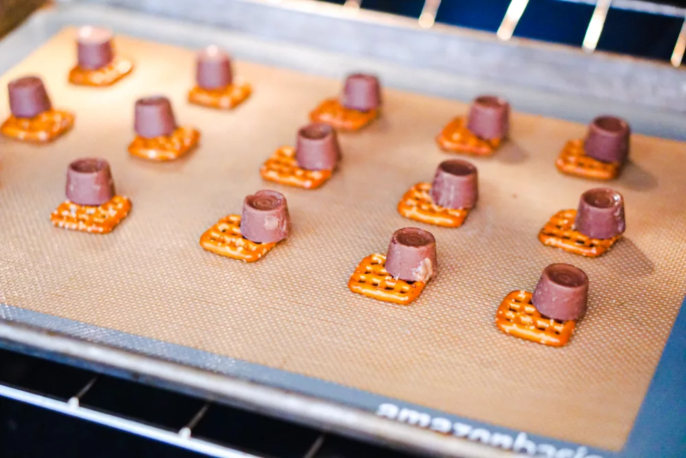 rolo on top of pretzels on a cookie sheet in the oven