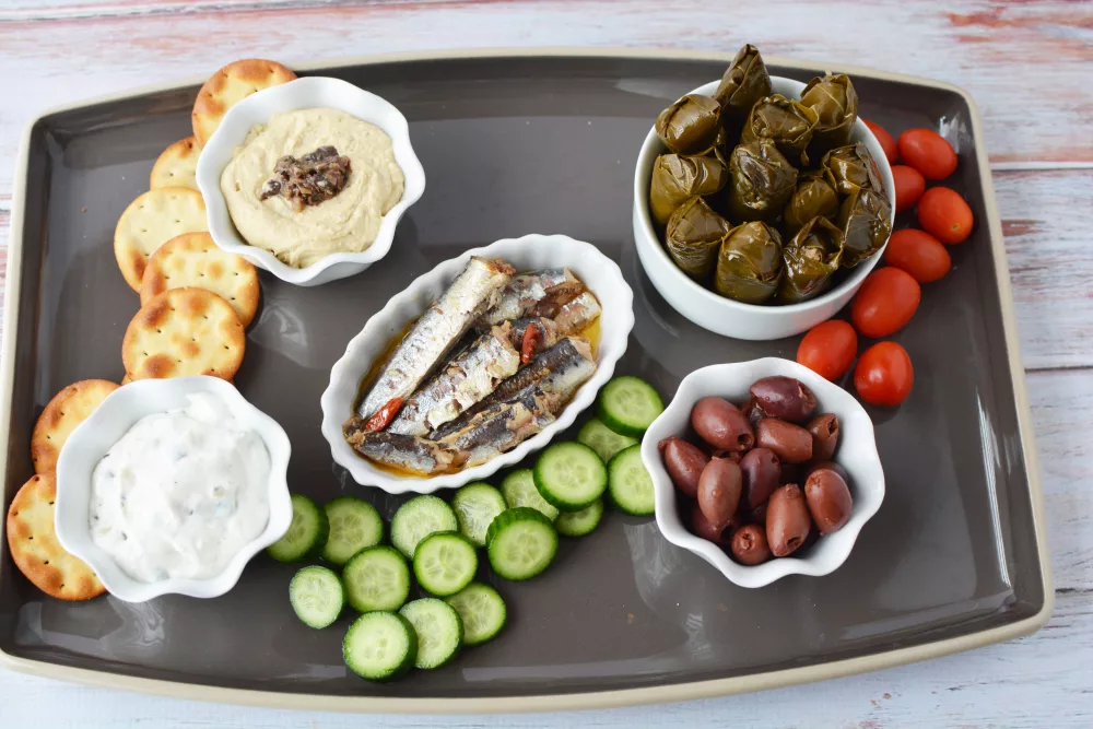 Greek Charcuterie Board filled with crunchy cucumbers, feta cheese, salami, pita crackers, sardines, and kalamata olives