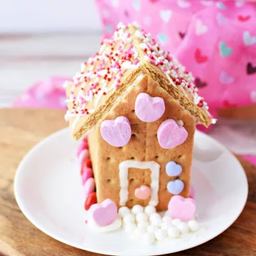 gingerbread house covered in red and pink sprinkles and candies