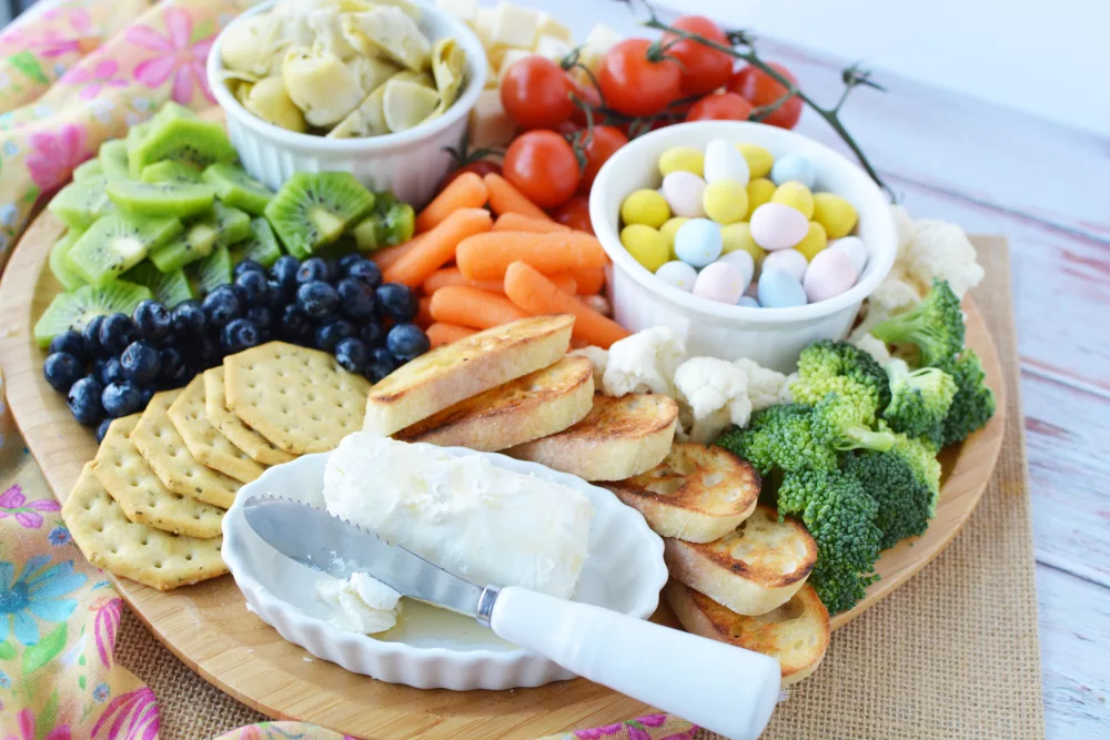 Epic Spring Charcuterie Board filled with fresh vegetables, fresh fruits, crackers and cheese and Easter candies