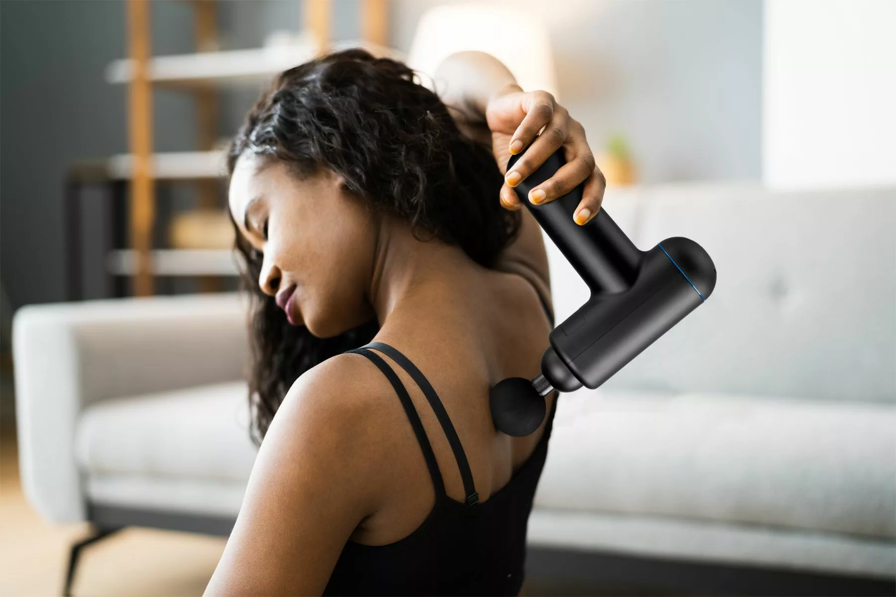 woman using a iLive Portable Cordless Massage Gun on her back