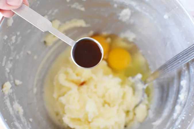 vanilla extract being added to a bowl of cookie ingredients