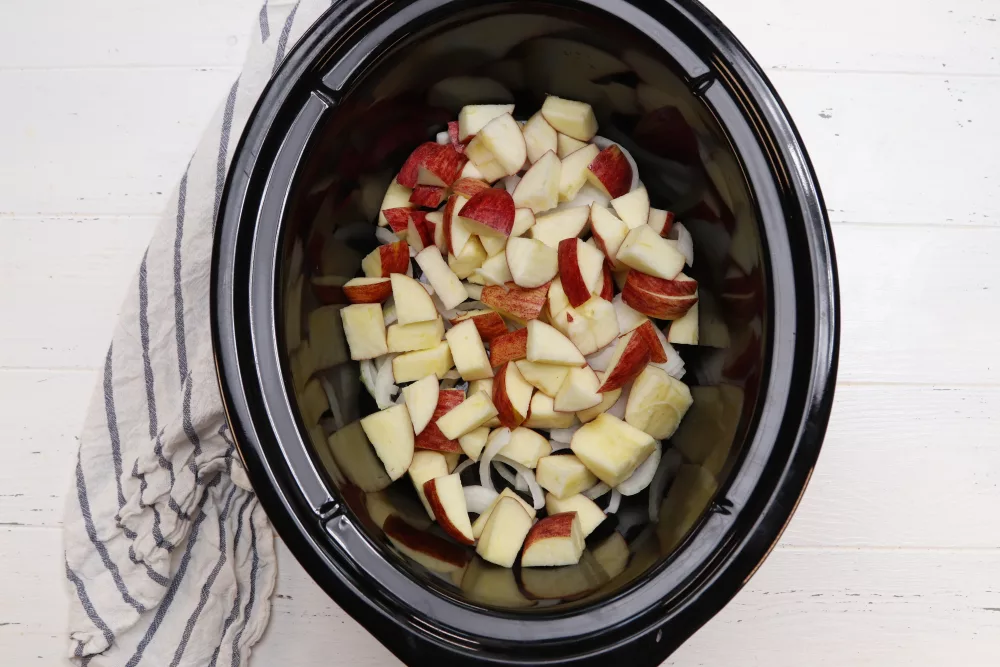 red apples and potatoes in the bottom of a crock pot