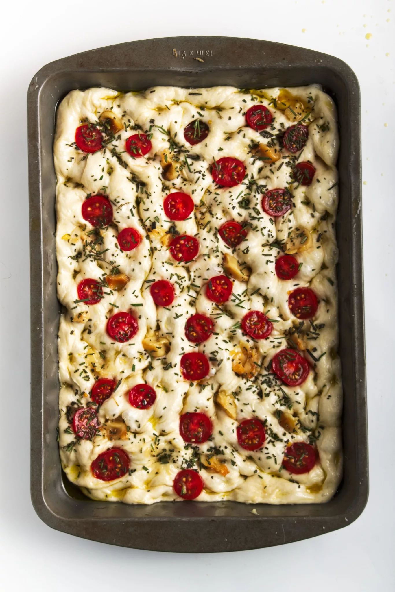 bread dough filled with garlic cloves, rosemary and halved tomatoes