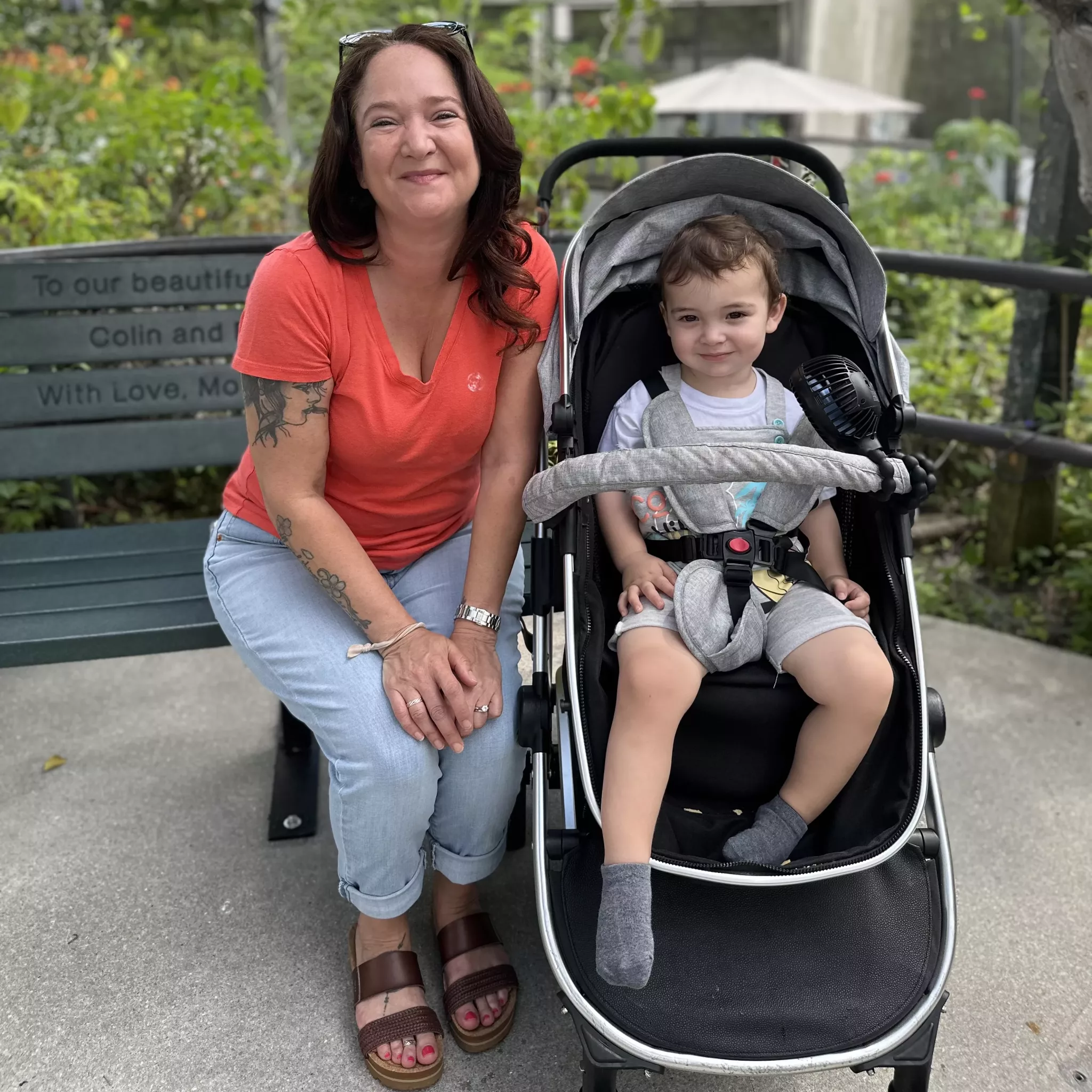 woman wearing LEVIS jeans, an orange tee shirt and REED High Vista Sandals with her grandson in a Stroller at Butterfly World in Coconut Creek Florida