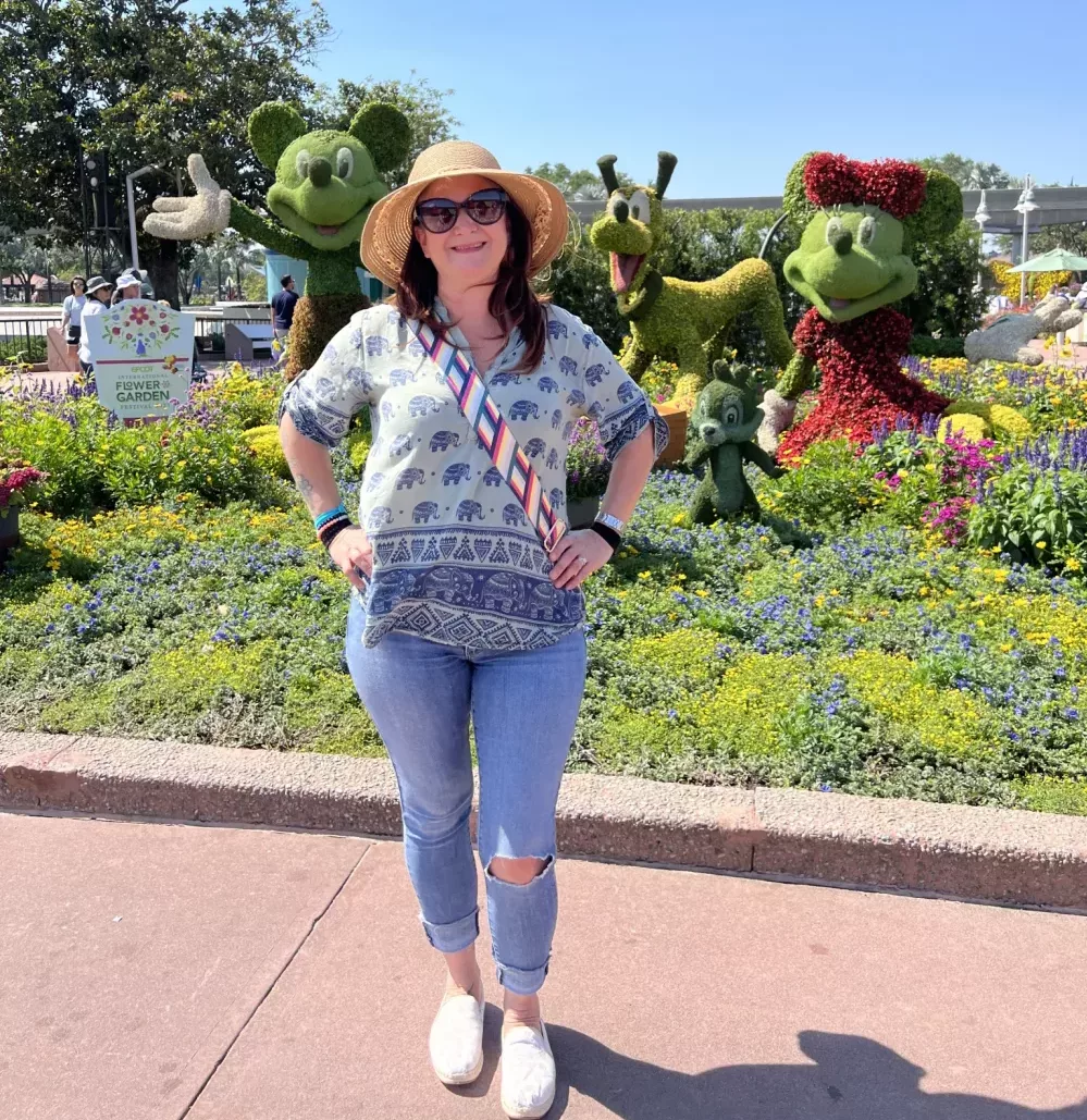 woman wearing a pair of distressed Levis jeans, an elephant shirt and TOMS shoes with a sunhat at EPCOT