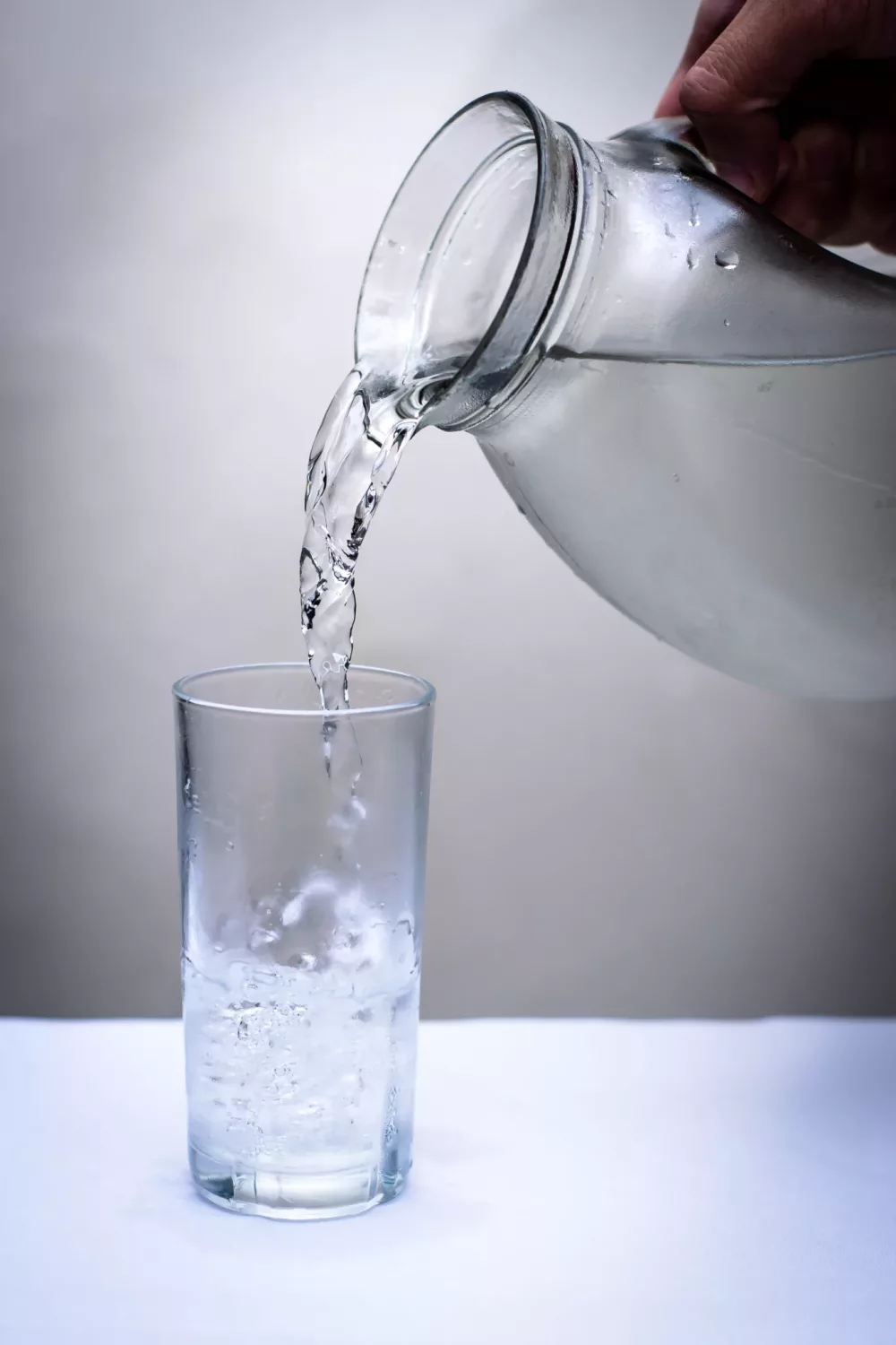 glass of water being poured from a glass pitcher
