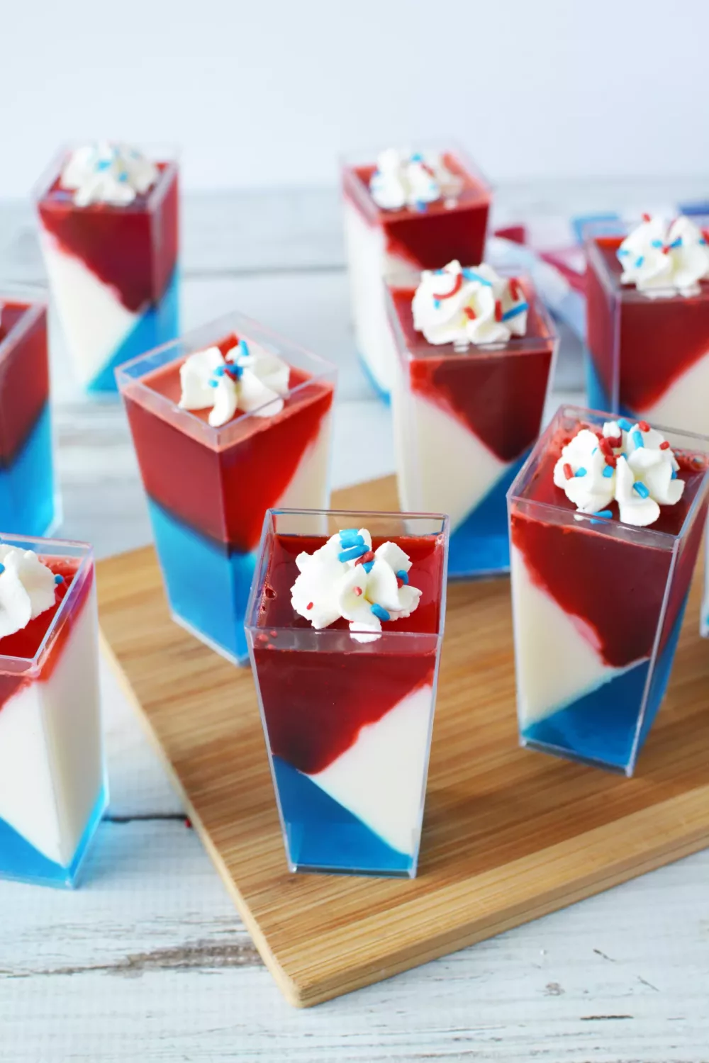 Red White and Blue JELLO Shots in mini cups with whipped cream and sprinkles on top