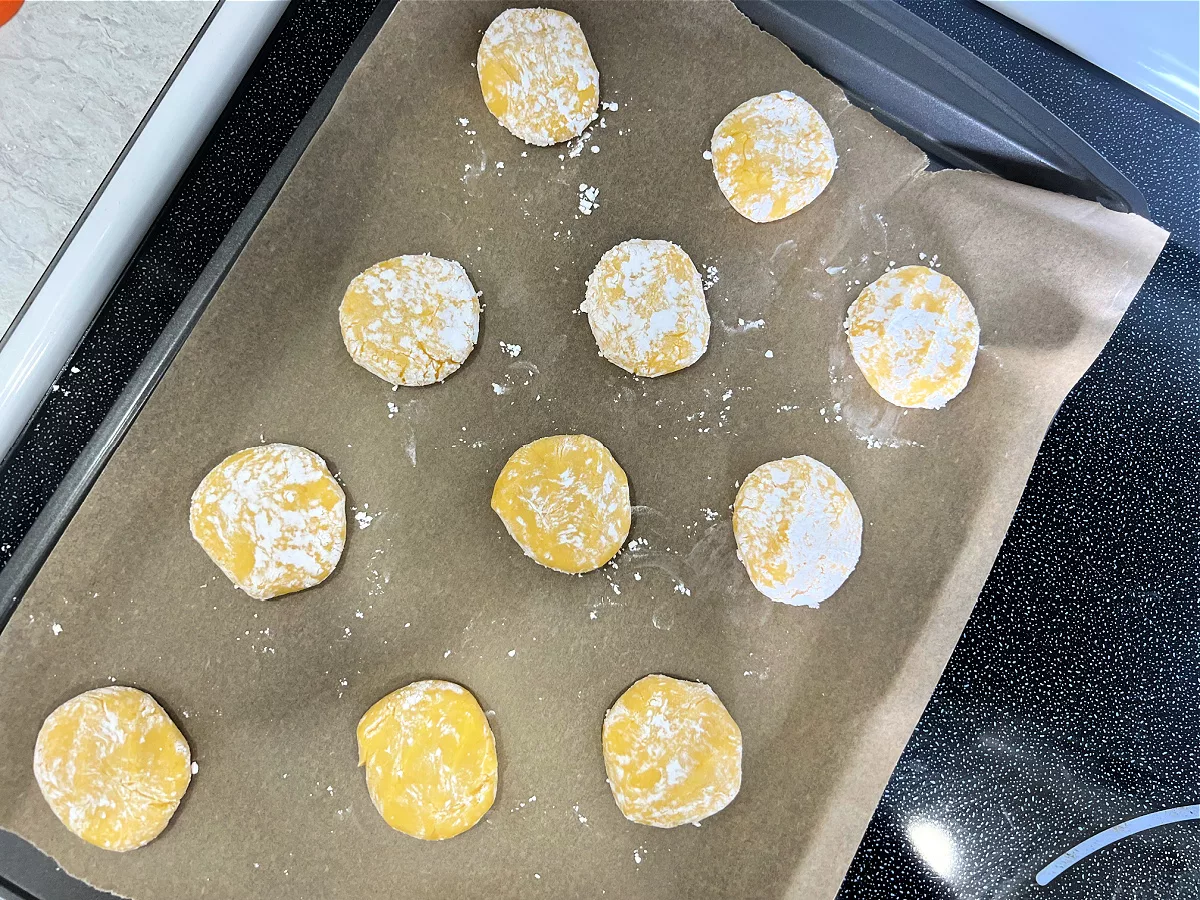 cookie dough balls rolled in powdered sugar and placed on a parchment paper lined baking sheet