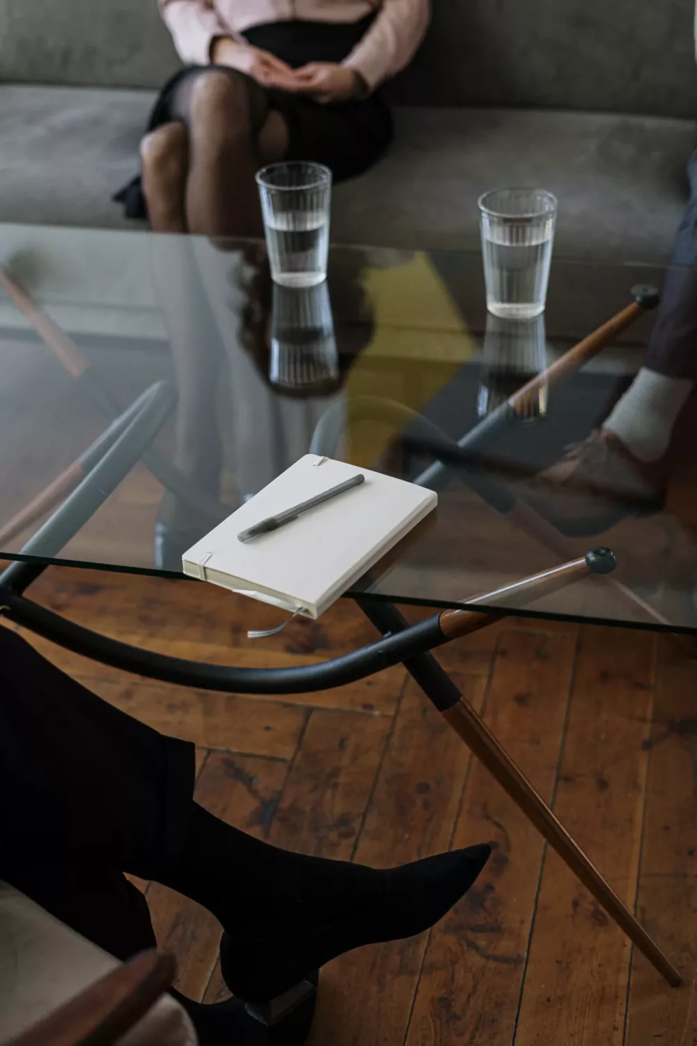 notepad sitting on a table with a pen and glasses of water