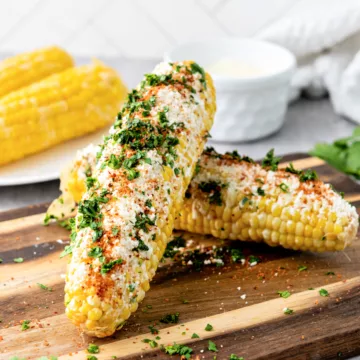 corn on the cob covered in crema cheese, tajin and cilantro
